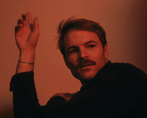 Jeremy Marshall Blanton poses for a press photo with his elbow on a table and hand in the air