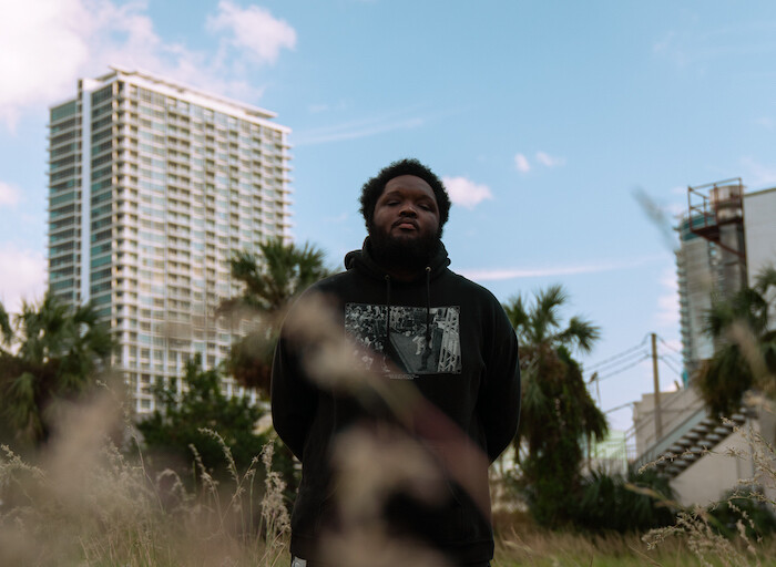 Wahid standing in a field in front of tall buildings